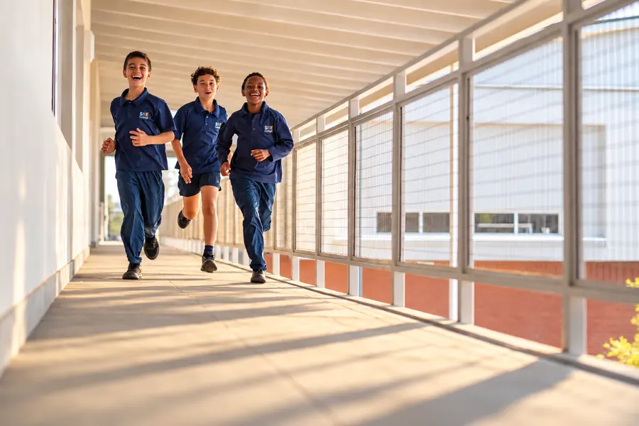 Prep children running along a covered walkway between the classrooms