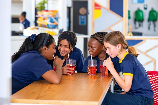 Four Prep girls sharing juice and a laugh around a table at Khula Café