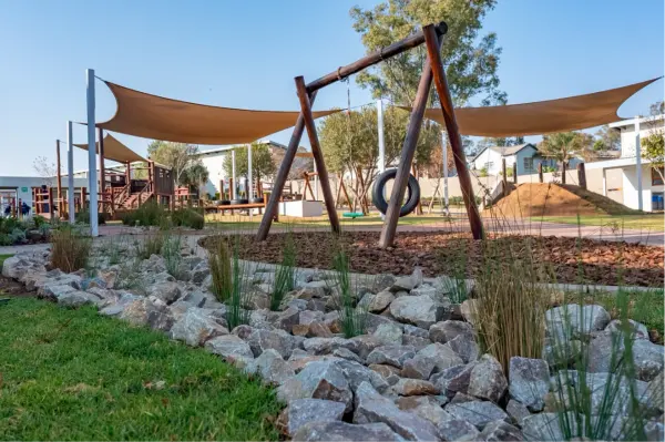 The Preschool playscape with a swing, shade sails and rockery