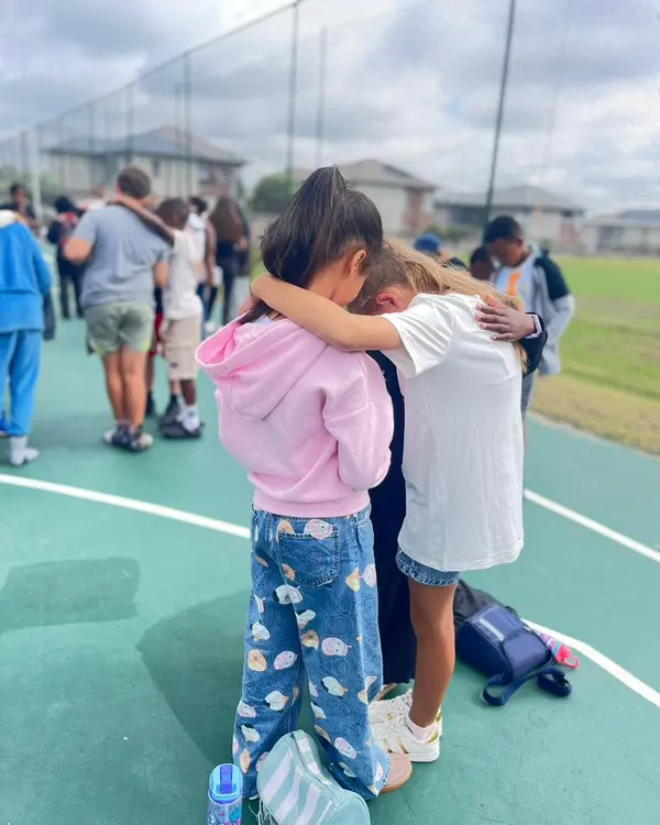 Two girls with their arms around each other, heads bowed in prayer, at a ThriveYouth gathering