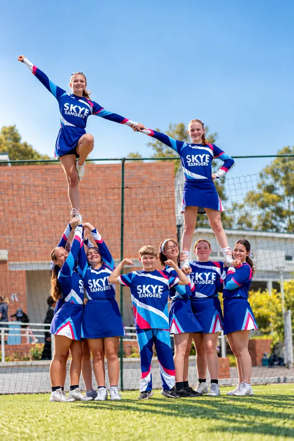 Cheerleaders lifting a flyer high in a pyramid
