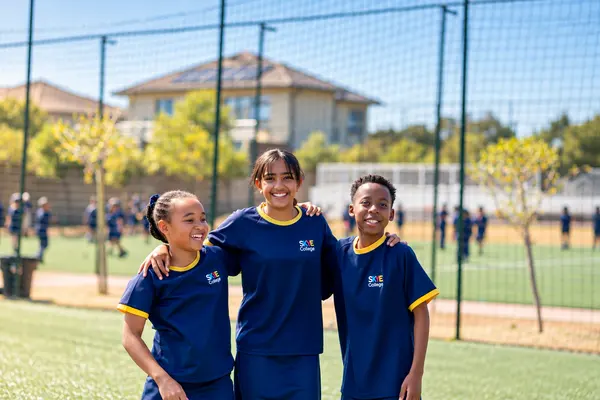 Three Senior Prep friends with their arms around each other on the sports field
